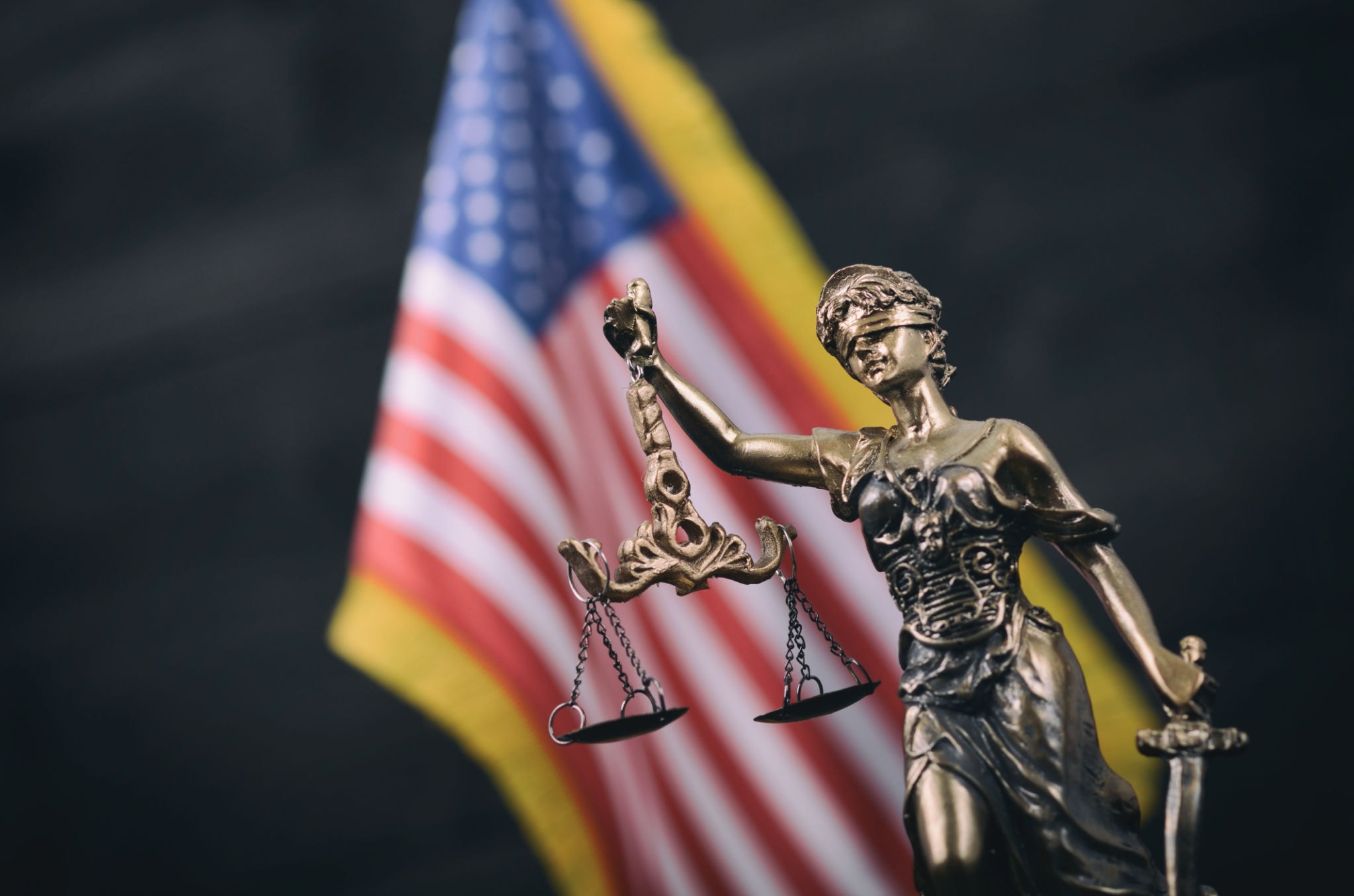 Lady Justice statue with American flag — Khemraj Law Firm PC